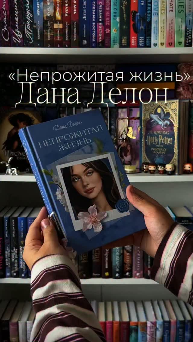 Книга Непрожитая жизнь в руках Оли на фоне книжных полок